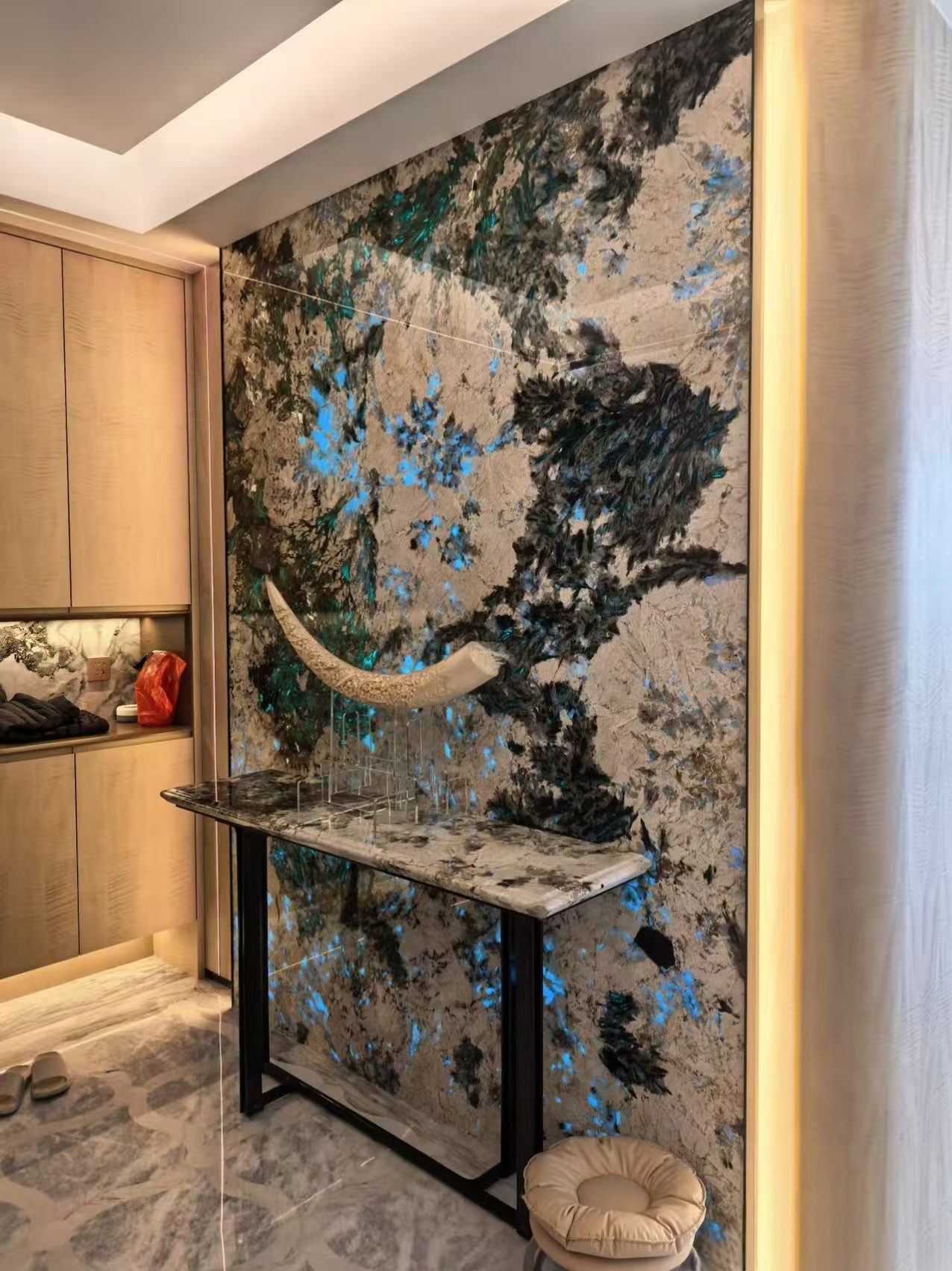 Illuminated blue and black natural stone feature wall with matching console
